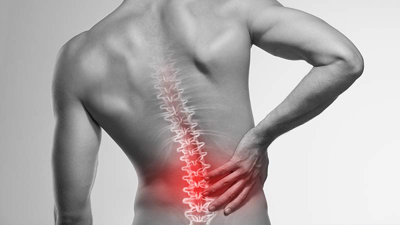 Physical back pain being demonstrated on a mans spine.