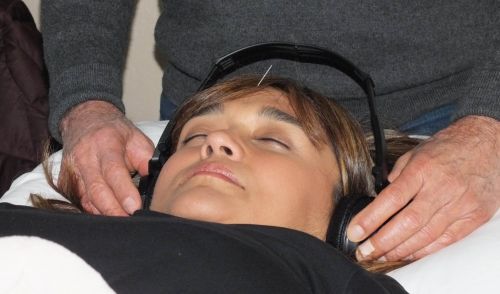 Patient receiving treatment from Juan in his clinic with headphones.